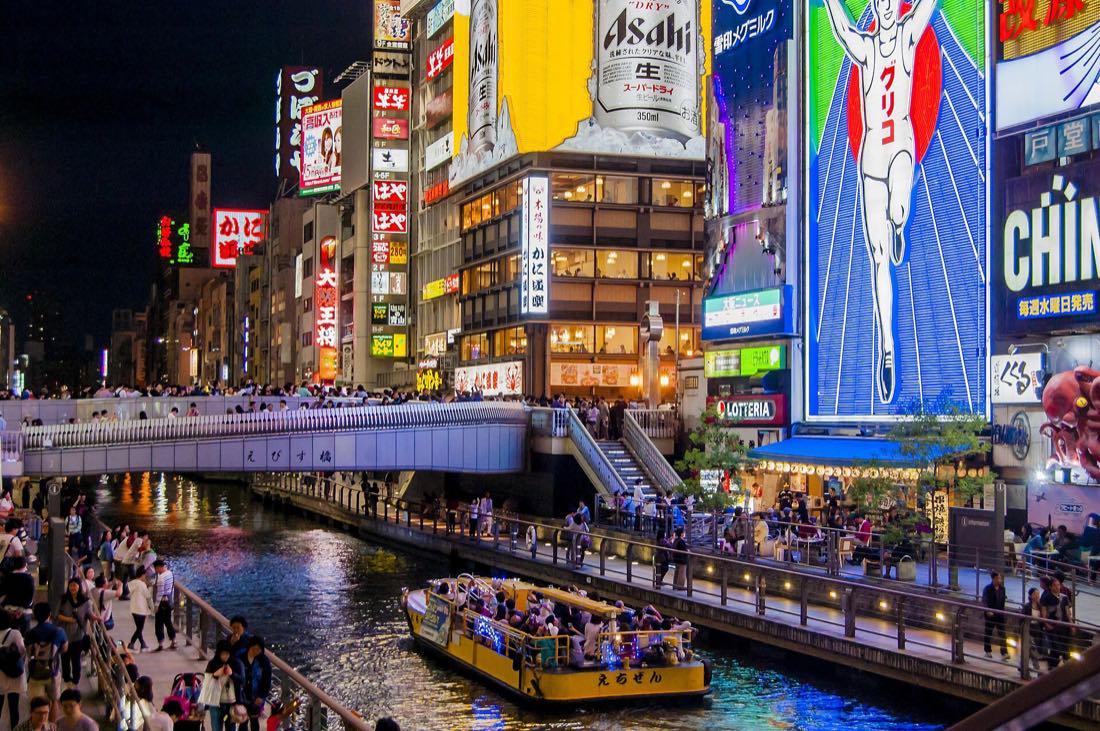 The Dotonbori canal at night, neon signs reflected in the water, Osaka